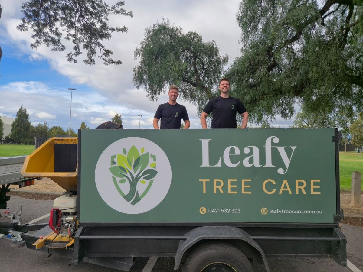 Chris and Henry from Leafy Tree Care standing behind their branded trailer
